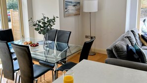 A modern dining area with a glass table, black chairs, and a breakfast setting including croissants and strawberries.
