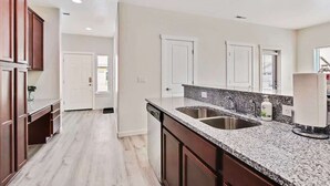 A kitchen with a granite countertop, double sink, and wooden cabinets. - Charming Centrally Located Treasure Valley Custom (Nampa)