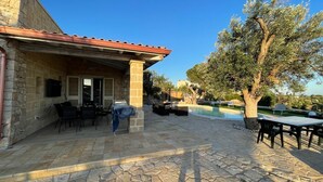 A stone patio with outdoor seating, a pool, and a tree. - Villa dei Desideri (Salve)