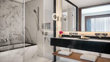 A modern bathroom with a glass-enclosed shower, a black marble vanity, and a large mirror.