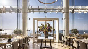 Un comedor moderno con una gran mesa de cristal, varias sillas y vistas al mar.