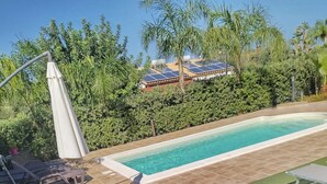 Ein Whirlpool, umgeben von üppiger Vegetation, ein Schwimmbecken und Liegestühle.