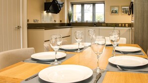 Un coin repas avec une table en bois mise pour quatre personnes, comprenant des assiettes, des verres et des couverts.