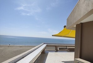 A balcony with a view of the sea, a yellow awning, and a Mitsubishi air conditioning unit.
