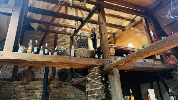A rustic interior with exposed wooden beams, a stone wall, and a wooden ceiling.