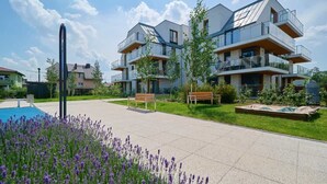 A modern residential building with multiple balconies, a swimming pool, and a well-maintained garden. - Stylish Apartment with Balcony | Private Parking (Wroclaw)