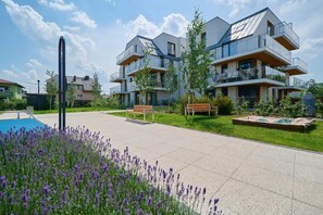 Un immeuble résidentiel moderne doté de nombreux balcons, d’une piscine et d’un jardin bien entretenu.