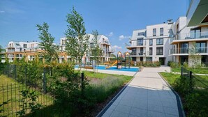 A residential complex with modern architecture, a playground, and a paved walkway. - Stylish Apartment with Balcony | Private Parking (Wroclaw)