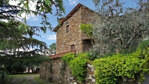 A stone building with a small window and a door, surrounded by greenery. - Casa Citille (Greve in Chianti)