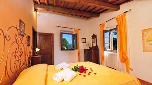 A room with a bed, a wooden ceiling, a window with curtains, and a radiator. - Casa Citille (Greve in Chianti)