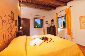A room with a bed, a wooden ceiling, a window with curtains, and a radiator.