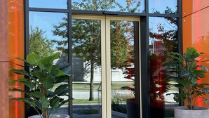 Une entrée moderne, avec des portes en verre et de grandes plantes en pot.