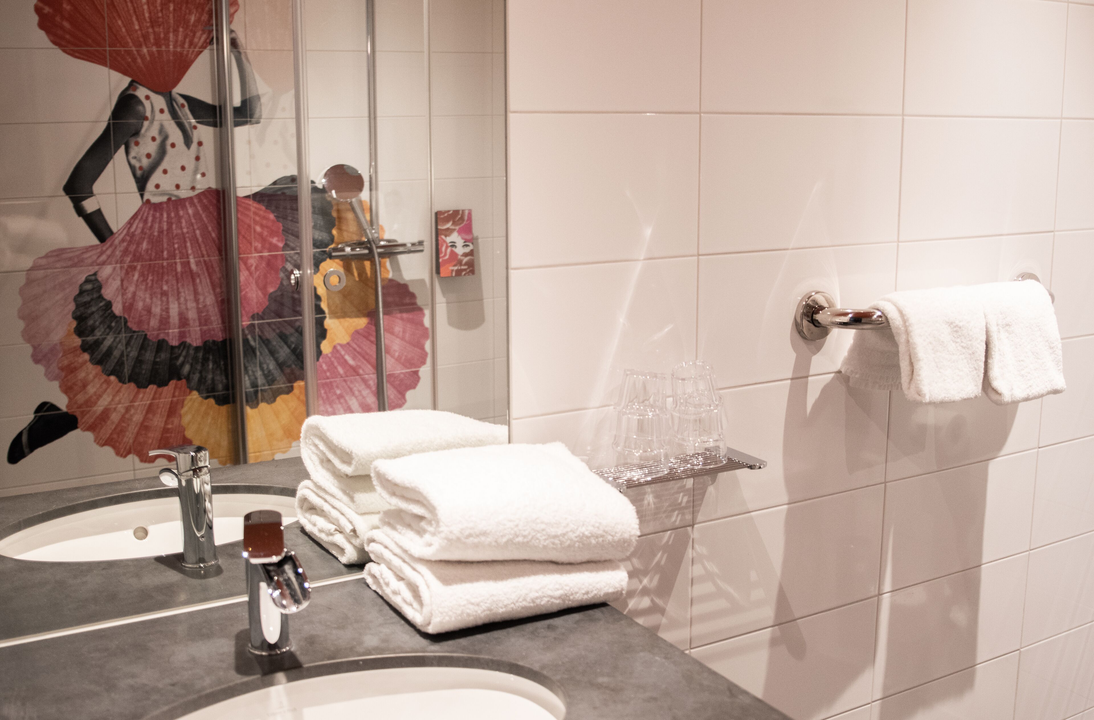 A bathroom with two sinks, a mirror, and a towel rack.