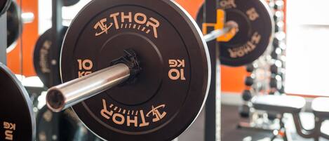 A weightlifting bench with a barbell and weight plates labeled "THOR FITNESS."