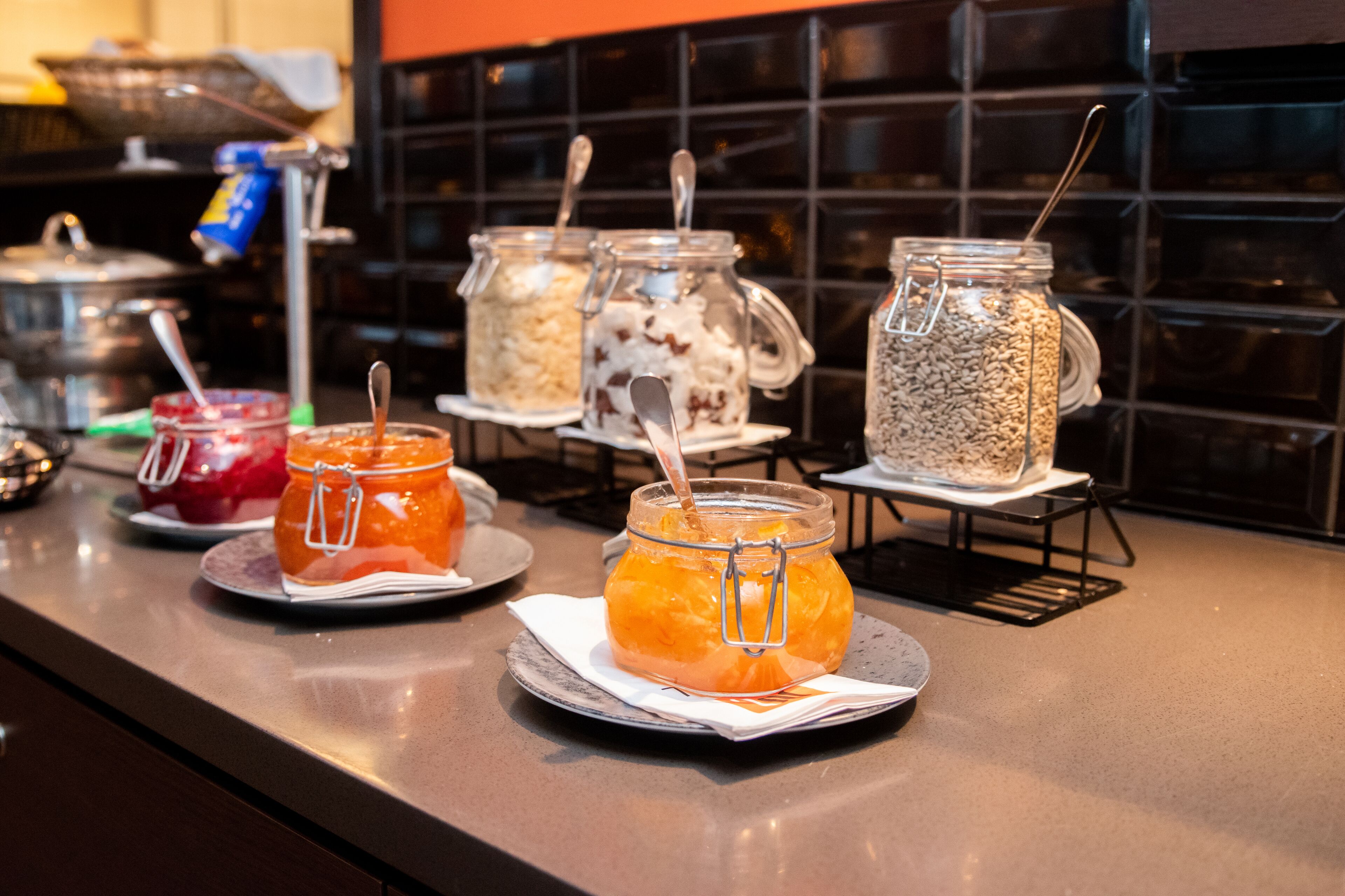 Zona de buffet con diferentes alimentos en frascos y recipientes sobre una barra.
