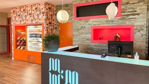 Un comptoir d’accueil au design moderne, un distributeur automatique et un mur décoratif orné d’un motif en pierre.