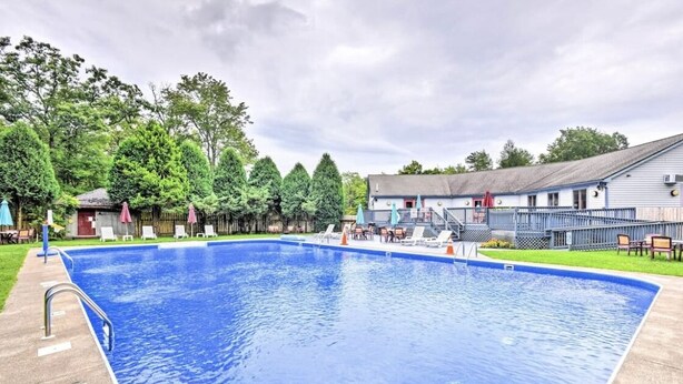 A rectangular swimming pool with a metal ladder on one side, surrounded by lounge chairs and umbrellas. - Mountain gateway in the beautiful Lake Harmony (lake harmony)