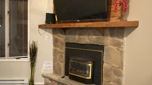 A stone fireplace with a television on a wooden shelf above it. - Mountain gateway in the beautiful Lake Harmony (lake harmony)