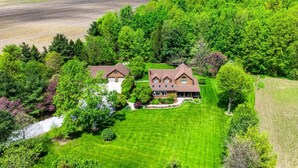 A large house with a well-maintained lawn and surrounding trees. - Private Log Estate by Winery | Trails & Fire Pit (Kingsville)