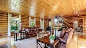 A log cabin interior with a leather sofa, a round coffee table, and a lamp. - Private Log Estate by Winery | Trails & Fire Pit (Kingsville)