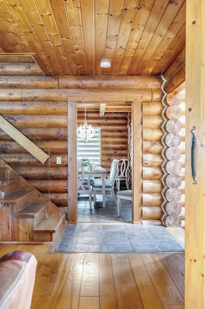 Un intérieur en bois avec un escalier, un coin repas et une vue sur une autre pièce.