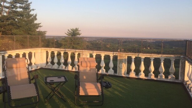 A rooftop terrace with two lounge chairs, a small table, and a view of the cityscape. - La Torre di Rua (SAN PIETRO DI FELETTO)