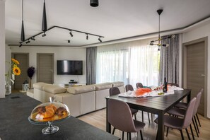 Ein modernes Wohnzimmer mit einer Couch, einem Fernseher, einem Esstisch und Stühlen.