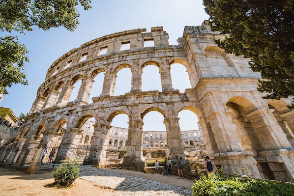 An ancient stone amphitheater with multiple arches and a central stage.