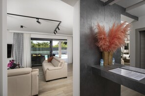A modern living room with a sofa, a dining area with a table, and a large window.