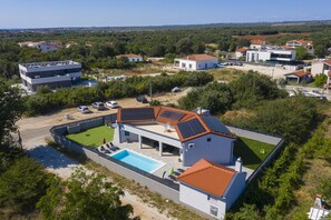 Et moderne hus med swimmingpool, solpaneler og udsigt over det omkringliggende landskab.