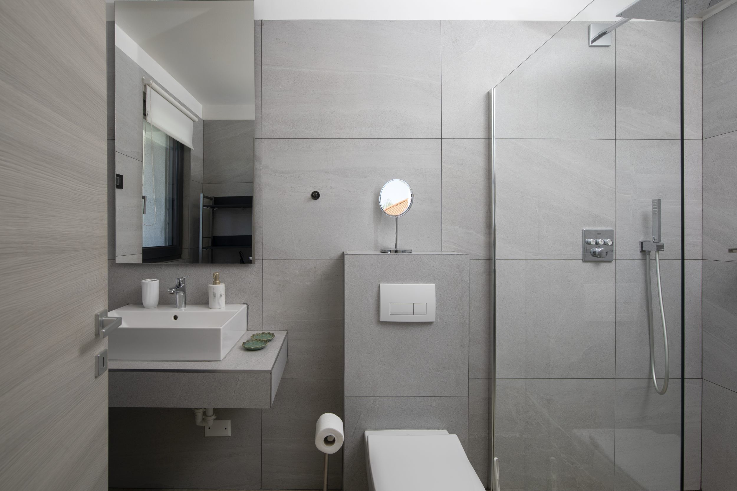 A modern bathroom with a sink, mirror, toilet, and shower.