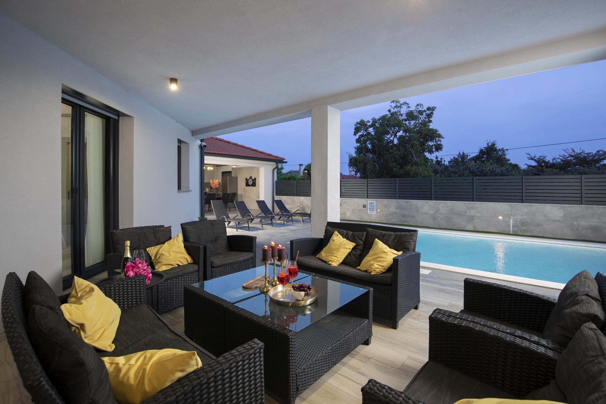 An outdoor seating area with wicker furniture and a pool.