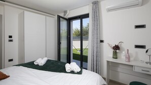 A modern bedroom with a bed, a desk, a bathroom, and a view of the outdoors. - Villa Speranza with pool (Pula)
