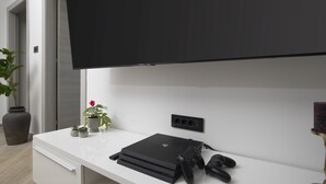 A modern room with a white console table, a flat-screen TV mounted on the wall, a gaming console, and two controllers. - Villa Speranza with pool (Pula)
