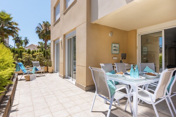 A patio with a dining table and chairs, a covered seating area, and a view of the surrounding buildings and greenery. - La Sirena (Javea / Xàbia)