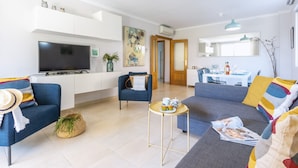Een moderne woonkamer met een bank, fauteuils, een salontafel en een televisie.