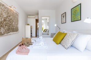 Ein Hotelzimmer mit einem Bett, einem großen abstrakten Gemälde, einem Spiegel und einer Tür zu einem Badezimmer.