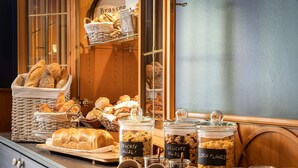 Un bufé de desayuno con panes, bollería y opciones de cereales.