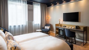 Una habitación de hotel con dos camas, un escritorio, una silla, un televisor y una mesita.