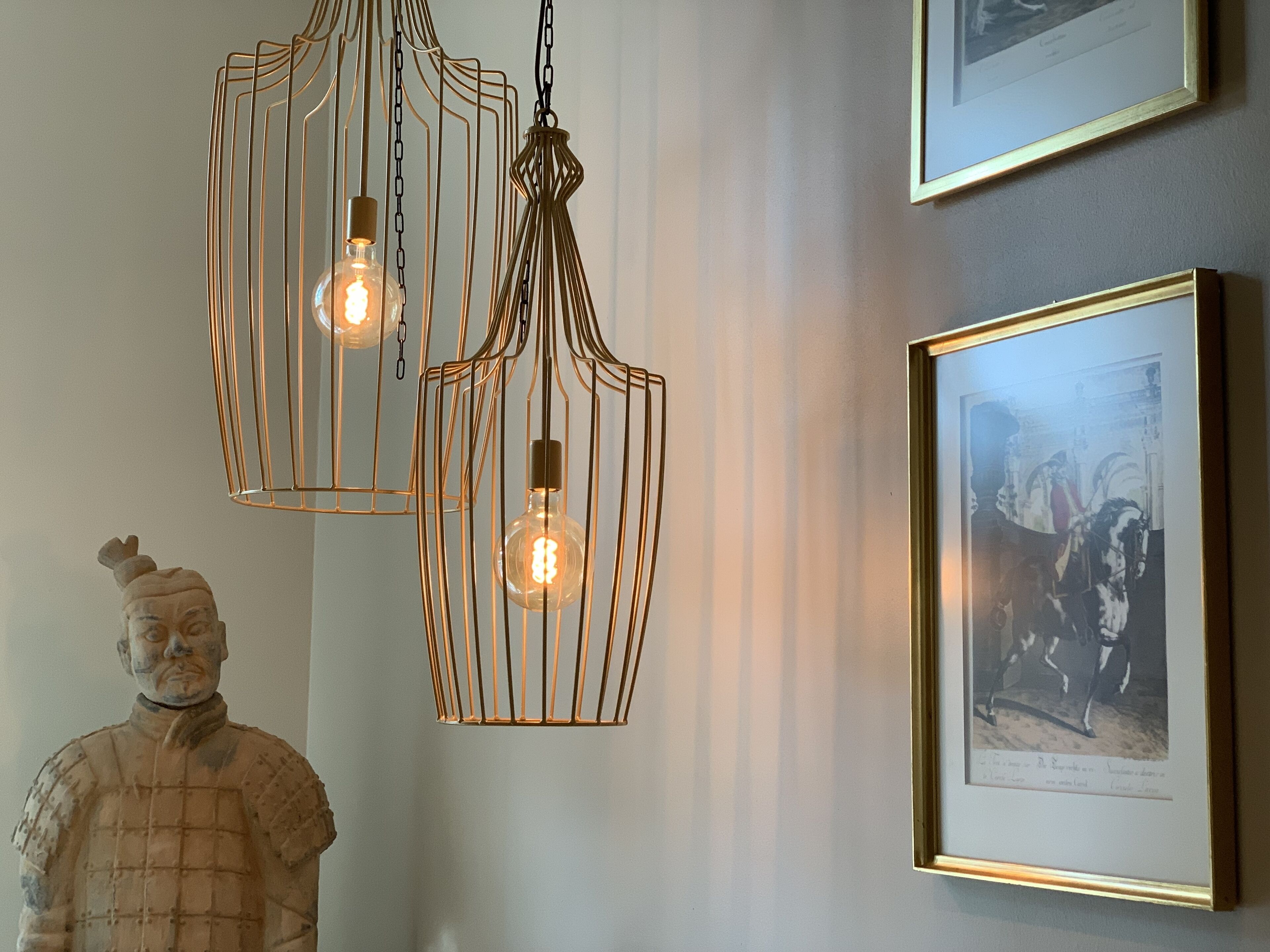 A room with a sculpture, two pendant lights, and a framed picture on the wall.