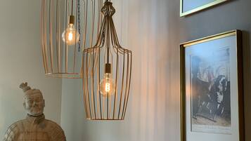 A room with a sculpture, two pendant lights, and a framed picture on the wall.