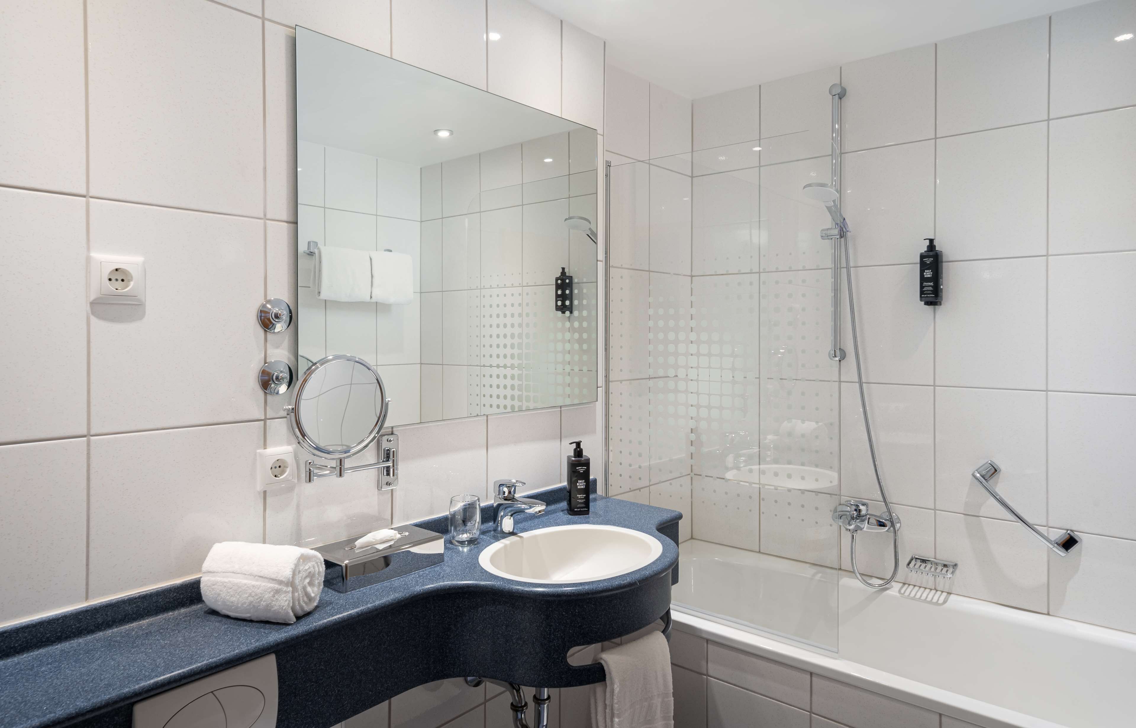 A modern bathroom with a large mirror, a sink, and a shower area.
