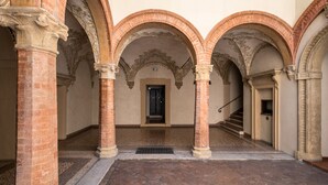 A corridor with arches, brick columns, and a staircase. - Rolandino Apartment by Wonderful Italy (Bologna)