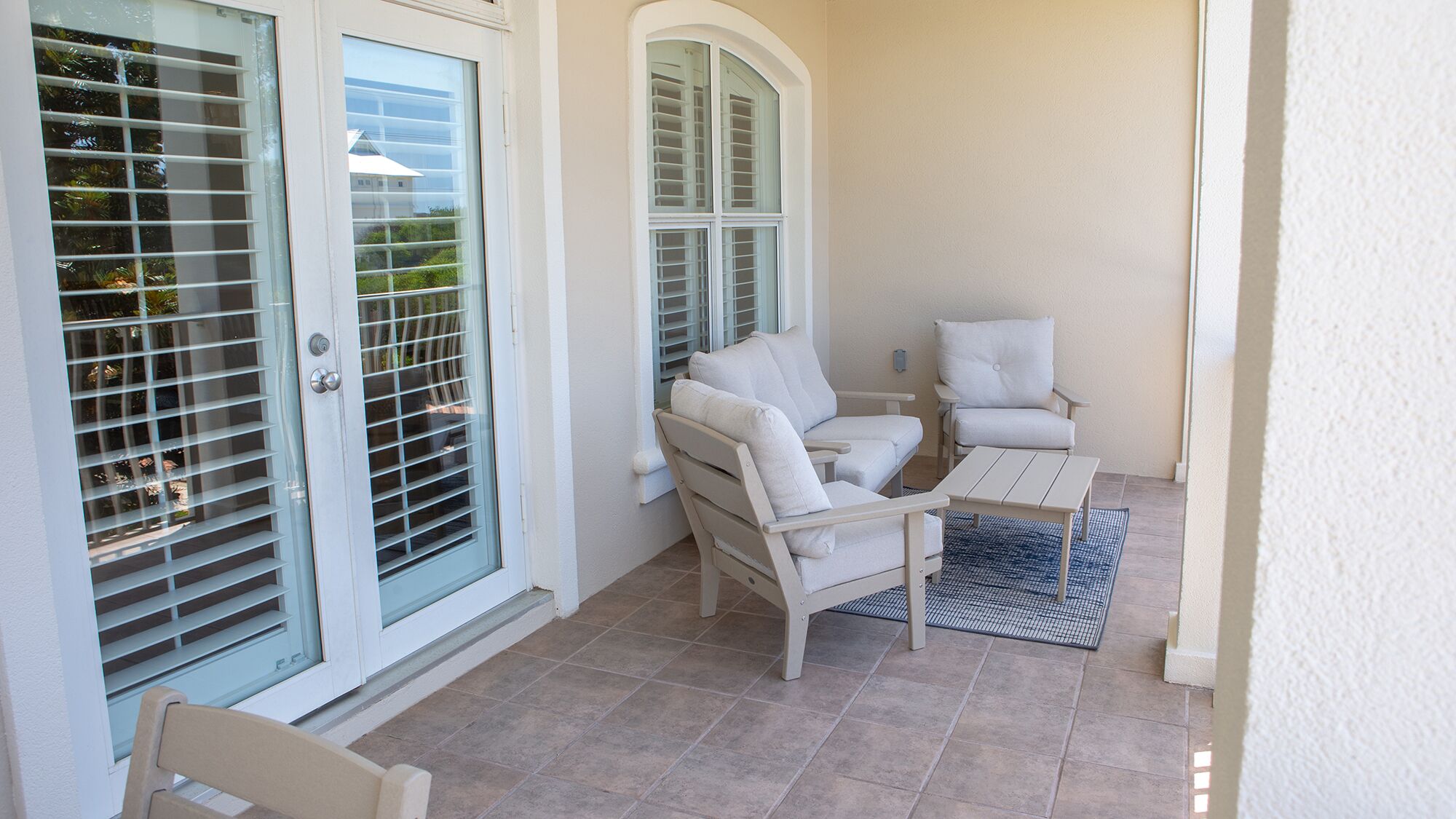 A patio with a white chair, a small table, and a blue mat.
