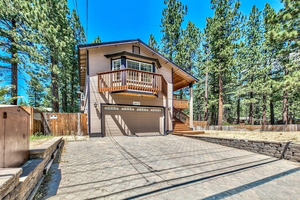 A two-story house with a balcony, a garage, and a driveway leading to the entrance.