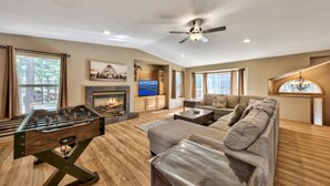 A spacious living room with a fireplace, a foosball table, a large sofa, and a ceiling fan.