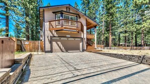 A two-story house with a balcony, a garage, and a stone retaining wall.