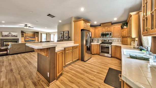 A spacious kitchen with wooden cabinets, a stainless steel refrigerator, a microwave, and a stove.