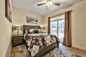 A bedroom with a bed, nightstands, a ceiling fan, and a window with curtains.