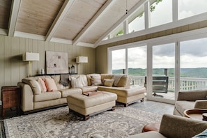 A spacious living room with a large sectional sofa, a coffee table, and a view of a deck with a railing.